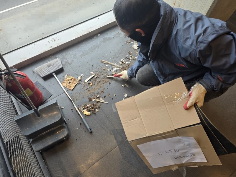 빗자루와 쓰레받기를 이용해 바닥의 폐기물을 박스에 담아 수거하는 작업