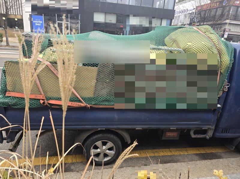 트럭에 대형 폐기물과 폐목재를 완전히 적재하고 그물과 끈으로 단단히 고정한 모습