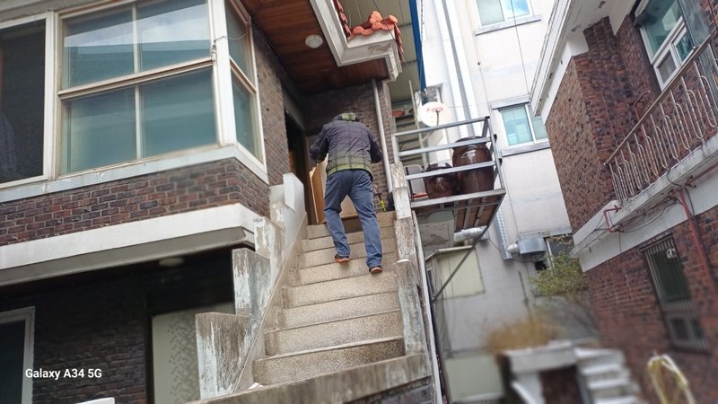 다음 폐기물 수거를 위해 건물 내부로 이동하는 작업자